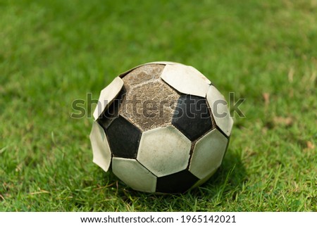 The small soccer ball put on green football field, Soccer ball with some pill off a hexagon leather cover.