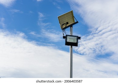 Small Solar Panel For Light In Street Or Park With White Clouds And Blue Sky. Outdoor Lighting Pole With Small Size Solar Panel Power By Themself, New Technology And Energy Trend For Public Area