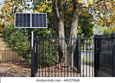 A small solar panel in the sun, operating an automatic opening gate.