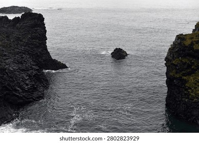 Small solitary rock stack between basalt cliffs at Arnarstapi in Iceland