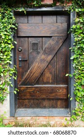Small Spanish style dark stained wood door to secret garden with grated window