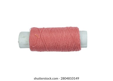 Small spool of pink sewing thread on white studio background. Essential tool for needlecraft and textile production. High quality cotton fiber for dressmaking kits.