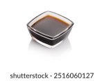 A small, square glass bowl contains rich, dark soy sauce with a glossy surface. The sauce is ideal for enhancing flavors in various culinary preparations.