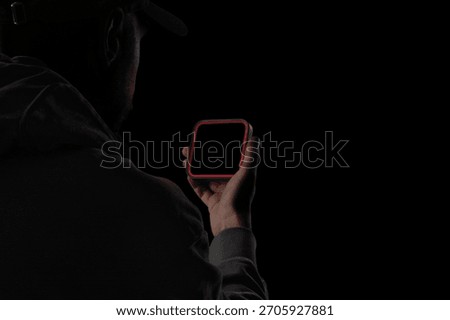 A small square handheld tech device with a glowing red outline, held by a person in dramatic low-key lighting. Suitable for UI previews, device branding, futuristic tech presentations