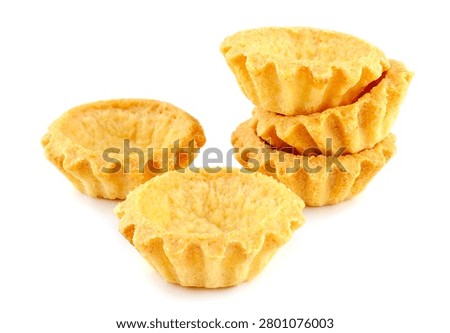 A small stack of empty golden shortbread tartlet shells ready for sweet or savory fillings. Clean commercial studio food isolation of traditional wavy pastry cases on a pure white background.