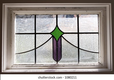 A Small Stained Glass Window With Green And Purple Sections