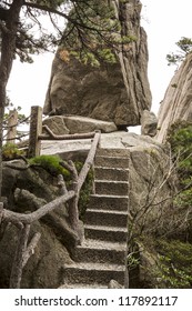 Small staircase in China's Yellow Mountain Trails with large rock and sky in background