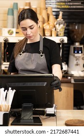 Small Startup Business Owner Concept. Waitress Girl In Apron Using Finger Touching Screen Of POS Terminal In Coffee Shop. Young Woman Staff In Coffeehouse Take Order And Print Receipt In Cafe