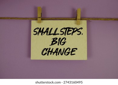 Small Steps, Big Change text written on paper card with rope and wooden clip hanging