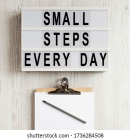 'Small steps every day' words on a lightbox on a white wooden background, top view. Overhead, from above, flat lay.  - Shutterstock ID 1736284508