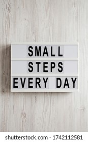 'Small steps every day' words on a lightbox on a white wooden surface, top view. Overhead, from above, flat lay.  - Shutterstock ID 1742112581