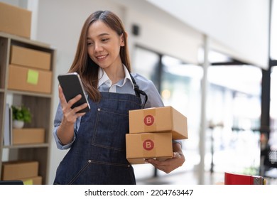 small stock business owner holding phone and retail package parcel boxes checking commercial shipping delivery order on smartphone using mobile app technology. - Shutterstock ID 2204763447