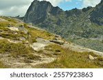 Small stone pyramids on a steep mountainside overlooking the picturesque peaks on a clear summer day. Natural park Ergaki, Krasnoyarsk region, Siberia, Russia.