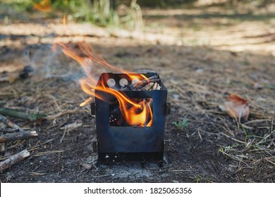 Small bushсraft stove. Wood chips are burning in the stove. Autumn in the forest.