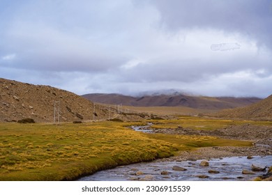 A small stream flows through the grassy fields at the foot of the mountain near Tso Kar, Thukje, Ladakh, India