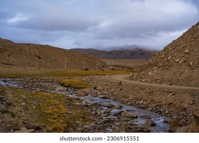 A small stream flows through the grassy fields at the foot of the mountain near Tso Kar, Thukje, Ladakh, India
