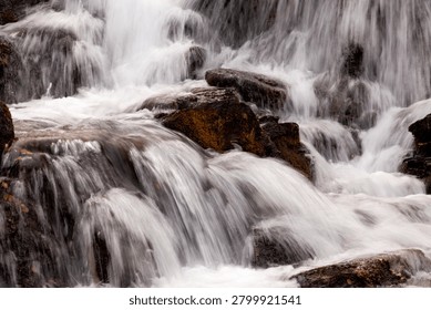 A small stream flows through the valley along a mountainside. Rocks and cliffs block its path and force the water to take new routes. 