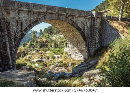 Small stream passing between stones under a Roman stone bridge overlooking the rural landscape in the Serra da Estrela Natural Park, Loriga PORTUGAL