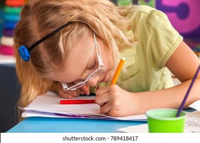 Small Students Painting In Art School Class. Child With Glasses Drawing By Paints On Table. Children's Myopia Because Of Sitting Incorrectly.