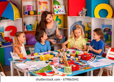 Small Students With Teacher Finger Painting In Art School Class. Mom And Kids At Home. Children With Teacher Preparing Exhibition Of Children's Drawings. Favorite Children's Teacher.