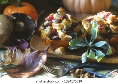 Small Stuffed Acorn Squash With Sausage, Dried Cranberries, Mushrooms, Sourdough Bread, Walnuts And Sage.  Autumn Decorations And Mushrooms Surround Wooden Plate.