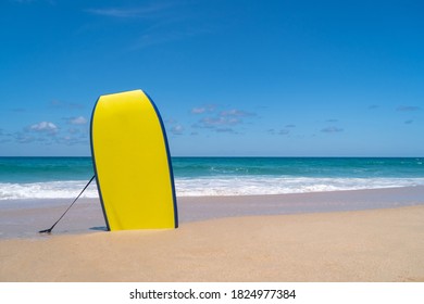 Small surfboards on sand at summer beach with sun light and blue sky background.