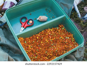 Small, sweet multicolored pieces in a plastic container. Soy pieces used as bait for carp fishing. Fragrant bait for carp fishing on carp baits. Bait for fishing in the form of small pieces. - Shutterstock ID 2292157429