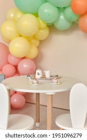 Small Table And Chairs With Bunny Ears In Children's Room Interior. Rainbow, Colorful Balloon Arch, Decoration In Honor Of The Holiday, Birthday, Party