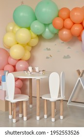 Small Table And Chairs With Bunny Ears In Children's Room Interior. Rainbow, Colorful Balloon Arch, Decoration In Honor Of The Holiday, Birthday, Party