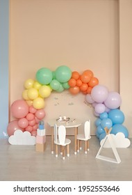 Small Table And Chairs With Bunny Ears In Children's Room Interior. Rainbow, Colorful Balloon Arch, Decoration In Honor Of The Holiday, Birthday, Party