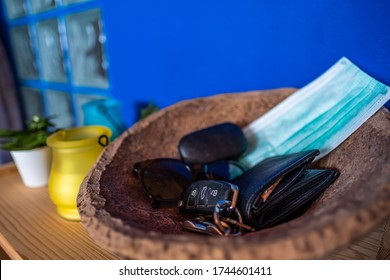 Small table at the entrance of a house with a wooden container in which there are keys, wallet, mask and sunglasses - Powered by Shutterstock