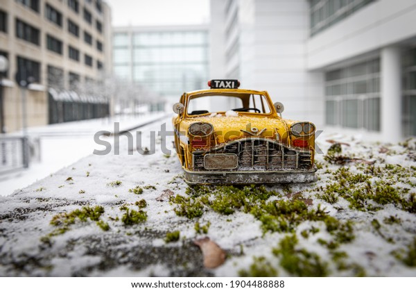 A small\
taxi car toy on grass covered with\
snow