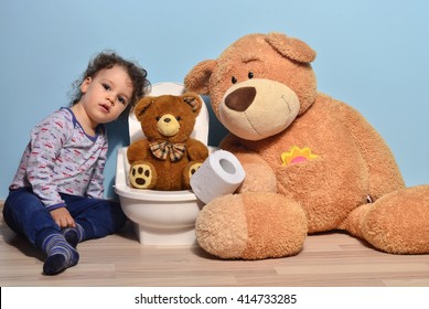 Small Teddy Bear Sitting On The Potty And Playing With Toilet Paper. Cute Kid Potty Training For Pee And Poo