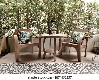 Small terrace patio with wooden table set in the garden on cement and vintage tile floor. Vintage tone background.