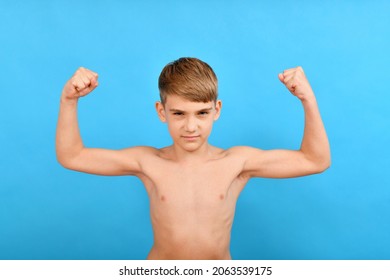 A Small Thin Boy Without Muscles Raised His Arms To The Top And Shows Biceps. Lean And Skinny Bodybuilder.