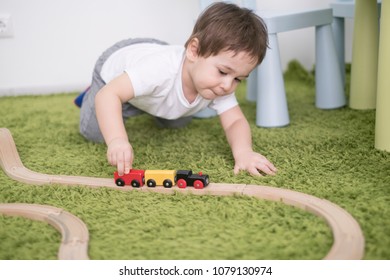 Small Toddler In A Colorful Children Room In A Nursery Or Preschool. Child Boy Playing With Toys Indicators At Home. Asian Baby 2 Years Old Plays Alone On A Green Carpet.