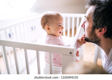 A Small Toddler Girl Standing In Cot With Her Father At Home.