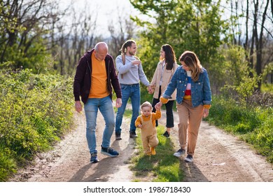 Small toddler with parents and grandparents on a walk outdoors in nature. - Powered by Shutterstock