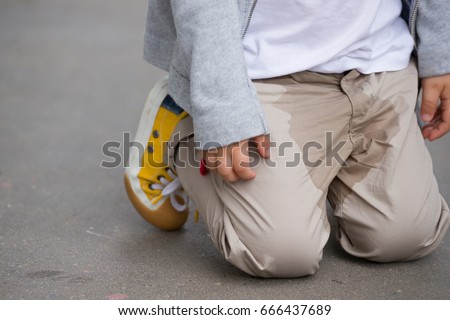 A  small toddler peeing on his pants on the street - Bed-wetting concept. Child pee on clothes.