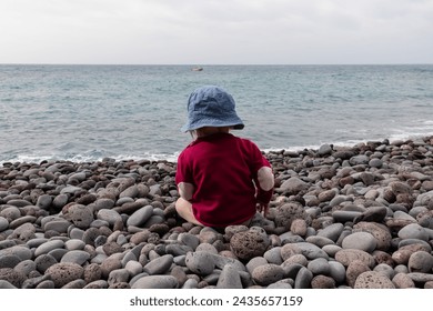 Small toddler playing on idyllic volcanic black stone beach of Praia Garajai, Canico, Madeira island, Portugal, Europe. Waves hitting shoreline of majestic Atlantic Ocean. Vacation with baby concept - Powered by Shutterstock