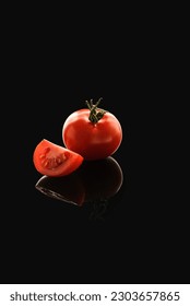 small tomato on the background with reflection with piece of tomato. High quality photo