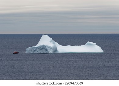 A small tour boat next to a large iceberg, Newfoundland and Labrador, Canada. - Shutterstock ID 2209470569