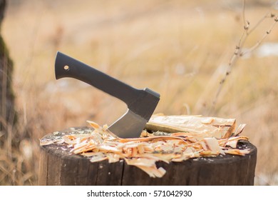 Small Tourist Axe Hatchet On Stump With Sawdust Shavings Outdoors. Carpentry Woodwork Concept