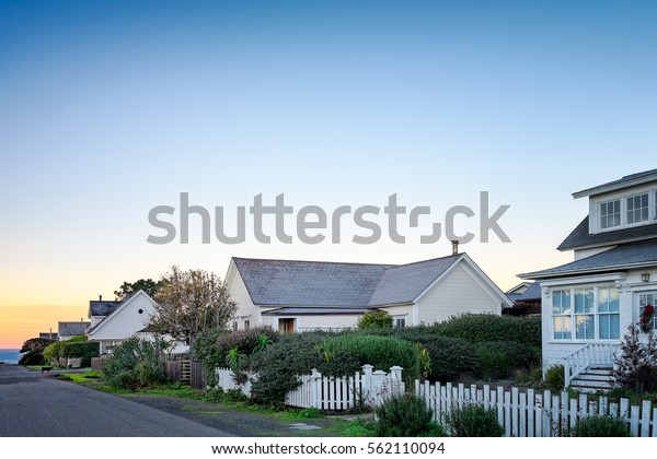 Small town America houses
with white picket fences in sunrise light. Background for old
fashioned nostalgic American town concept. Morning in America. Copy
space