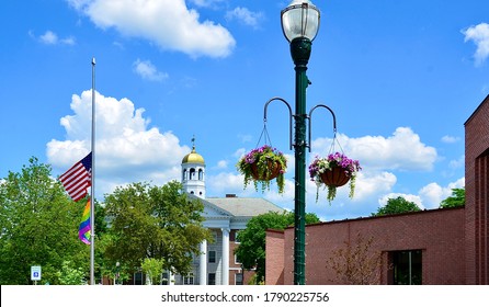 Small town, Auburn in New York.  Traditional summer street decoration with American flag and hanging baskets overflowing with flowers and foliage of all colors. City Hall as the background 