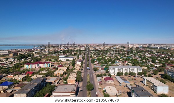 The small town of Balkhash is a view from a drone.\
A city in the middle of the steppe on the shore of Lake Balkhash.\
The metallurgical plant is smoking. Bad ecology. Low monotonous\
houses. Cars drive