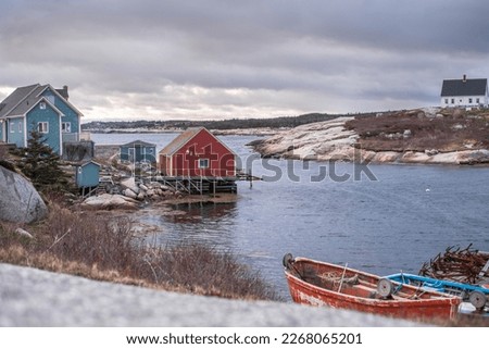Small town by the sea with old wooden cottages and fishing boat by a rocky shore in Nova Scotia, Canada