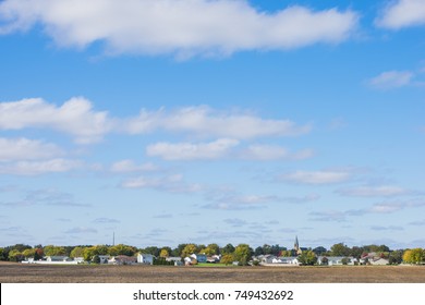 Small Town Midwest In Autumn With Harvested Field And Blue Sky Background