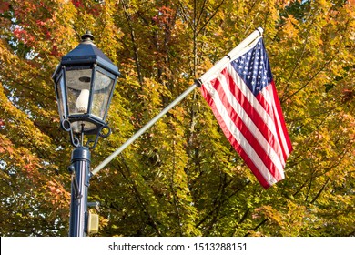 Small Town USA. Main Street Lamppost And American Flag Set Against Beautiful Fall Foliage In The Midwest Region Of America.