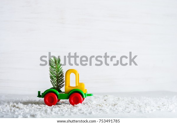 A small toy car is a\
crane. New Year and Christmas background. Mini Christmas trees from\
real spruce. Santa Claus made of paper. A blank for a postcard or a\
poster